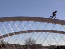 Biker rides over bridge arches