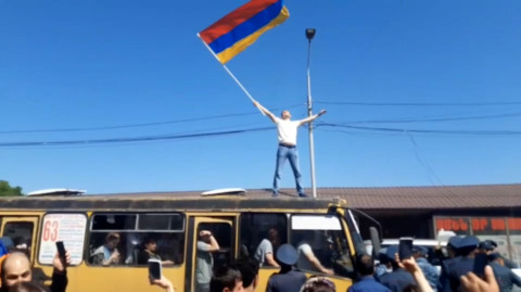 Ցուցարարը, ավտուբուսի վրա բարձրացած, ծածանում է Հայաստանի դրոշը